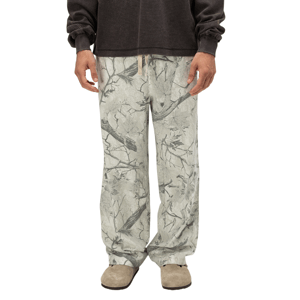 Gray sweatpants featuring a nature-inspired branch and leaf pattern, paired with light brown suede shoes and a dark long-sleeve top.