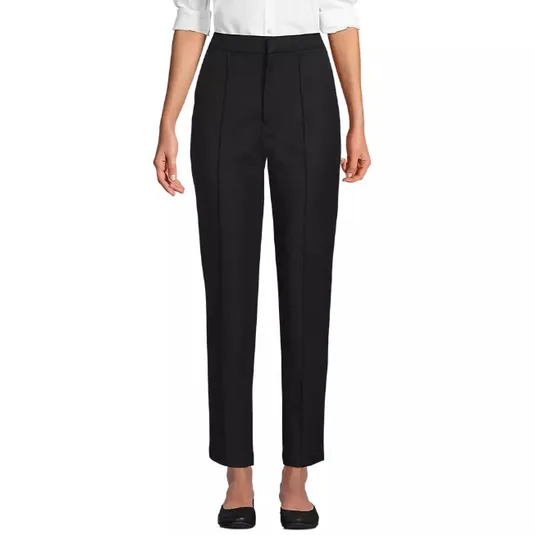 A pair of black, high-waisted straight-leg trousers paired with a white blouse and black shoes.