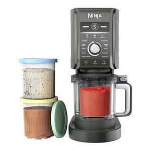 Ninja ice cream maker with a large mixing bowl filled with red ice cream and two extra ice cream containers, one with a cookie and cream flavor and the other with chocolate.