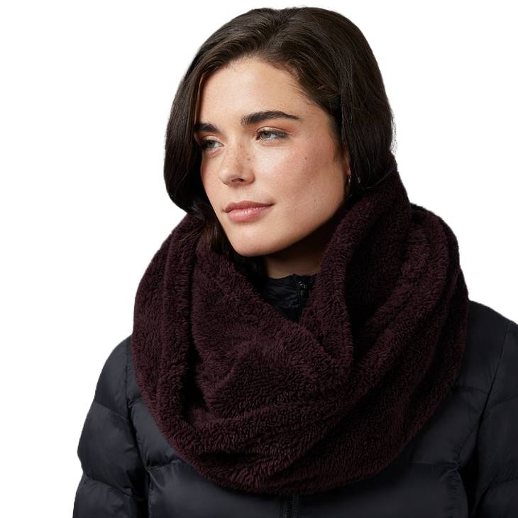 A woman wears a dark brown, plush infinity scarf and a black puffer jacket.