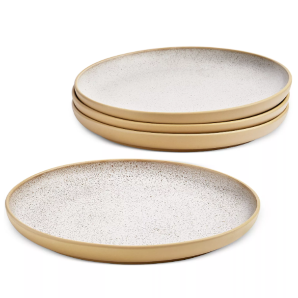 A set of four round plates with a speckled white surface and beige rims stacked together, featuring a minimalist design.