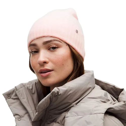 A woman is wearing a light pink beanie and a gray puffer jacket.