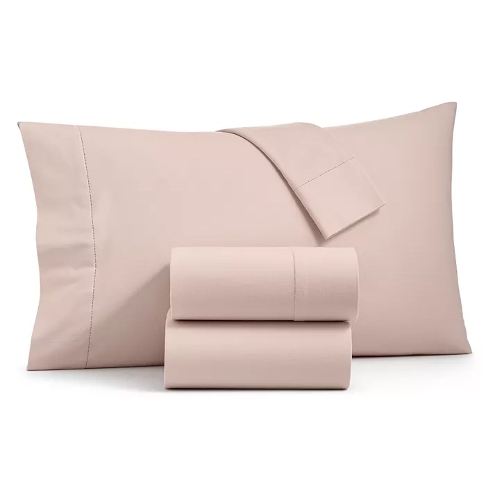 A set of light pink bed sheets with two pillowcases.