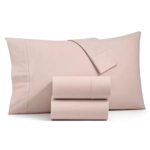 A set of light pink bed sheets with two pillowcases.