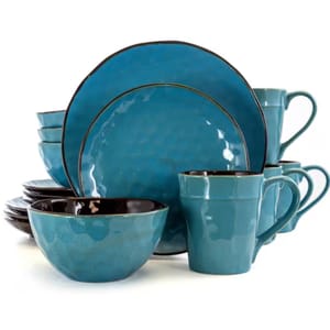 A 16-piece dinnerware set in glossy blue ceramic with a subtle textured finish, featuring plates, bowls, and mugs.