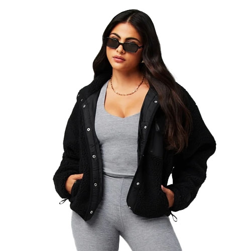 Woman wearing a black fleece jacket over a gray tank top and gray pants, accessorized with black sunglasses and a necklace.