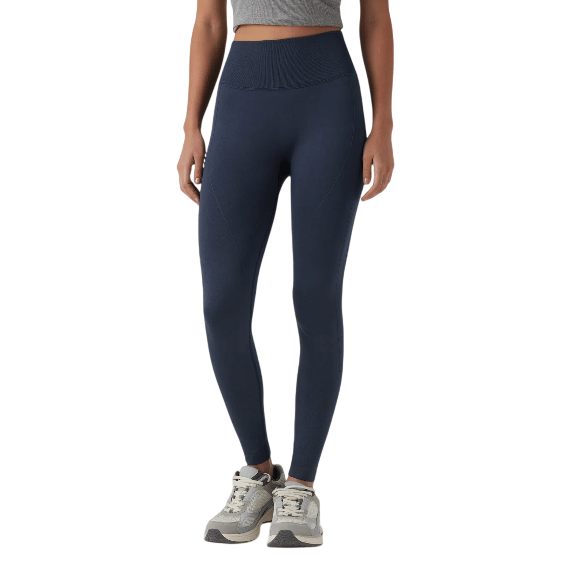 A person is wearing high-waisted, navy blue leggings paired with gray sneakers, standing against a plain background.