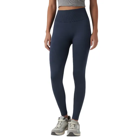 A person is wearing high-waisted, navy blue leggings paired with gray sneakers, standing against a plain background.