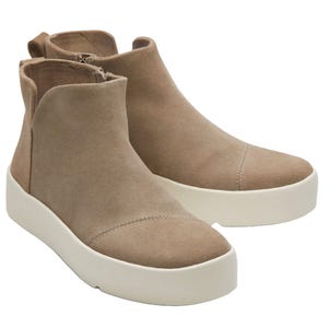 TOMS Platform Sneakers feature a taupe suede upper with a seamless design, high-top silhouette, and a thick white rubber sole. They include zippers on the side for easy wear and have visible stitching across the toe area.