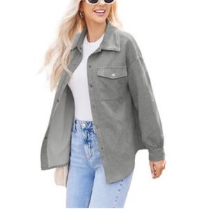 A woman is wearing a long-sleeve gray button-up shacket over a white top, paired with light blue high-waisted jeans. She completes the look with sunglasses.