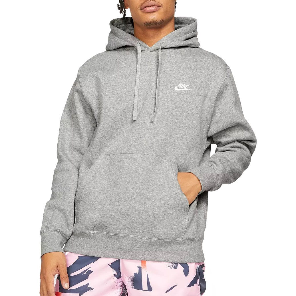 A person is wearing a gray Nike hoodie with a kangaroo pocket and drawstrings, paired with pink abstract-patterned shorts.