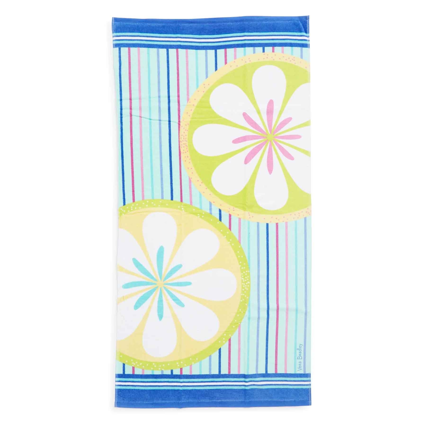 A beach towel with vibrant patterns featuring lime green and yellow circular floral designs on a colorful striped background in blue, pink, and green hues.