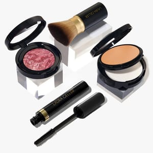 A makeup set featuring a pink marbled blush, powder foundation, black mascara, and a makeup brush, all with black packaging and gold accents.