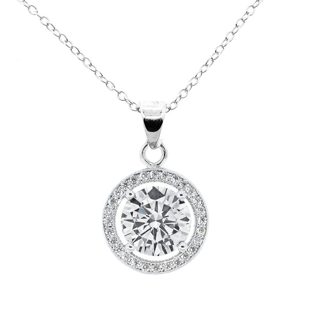 A silver chain necklace featuring a round pendant with a large central gemstone surrounded by smaller stones in a circular halo design.