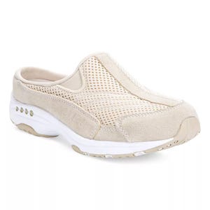 Easy Spirit Slip-On Mule Sneakers feature a beige color, mesh upper for breathability, and a cushioned white sole for comfort. They have a slip-on design with a low back for easy wear.