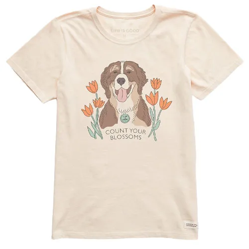 Cream-colored t-shirt featuring an illustration of a smiling dog surrounded by orange flowers and the phrase \“Count Your Blossoms\“.