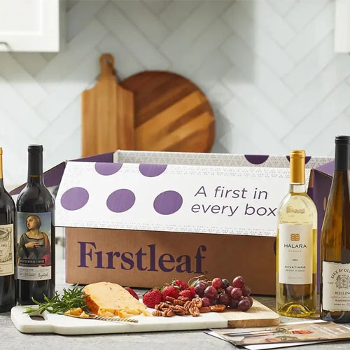 A Firstleaf subscription box is displayed on a kitchen counter alongside a selection of wines, cheese, and fruit.