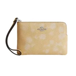 Yellow Coach wristlet with pebbled leather texture, featuring a subtle floral print and a metal logo.