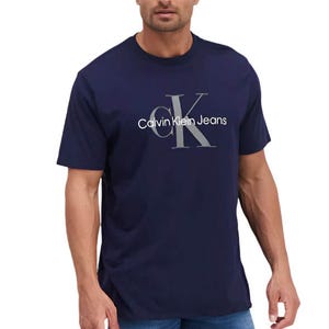 A navy blue Calvin Klein crew neck t-shirt with the \“CK\“ logo and \“Calvin Klein Jeans\“ printed on the front, worn by a man with blue jeans.
