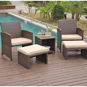 A patio set with two chairs, cushions, an ottoman, and a side table, next to a pool.