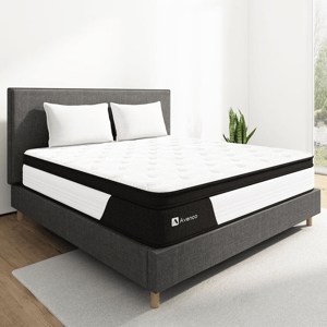 A modern bed setup with a plush Avenco mattress and two white pillows, set in a minimalistic room with a gray fabric bed frame and a snake plant by the window.