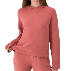 A person is wearing a matching set consisting of a long-sleeved, hooded top and pants in a muted pink color.