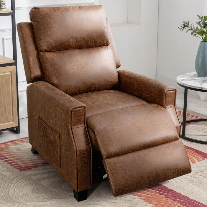A brown leather recliner chair with a footrest extended, featuring a side pocket, set on a patterned rug next to a small round marble table with a plant on top.