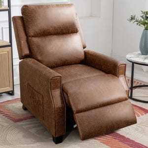 A brown leather recliner chair with a footrest extended, featuring a side pocket, set on a patterned rug next to a small round marble table with a plant on top.
