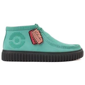 A turquoise Clarks shoe featuring a textured circle design on the side, with a black ribbed sole, and hanging tags displaying the collaboration with Pokémon.