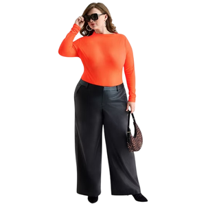 A person is wearing a bright orange long-sleeve top, wide-leg black leather pants, and black shoes, accessorized with large sunglasses, hoop earrings, and a small leopard-print handbag.