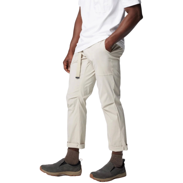 A man wearing a white T-shirt, beige cargo pants with a side pocket, and gray slip-on shoes with brown socks.