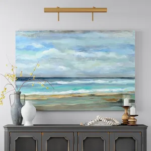 A seascape painting hangs above a wooden console table adorned with two vases, one with yellow berries, wooden candle holders with white candles, and a decorative bead strand.