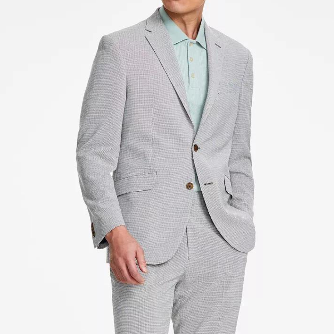 A man is wearing a light gray houndstooth-patterned suit with a pastel green shirt and brown buttons.