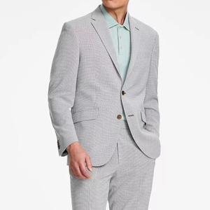 A man is wearing a light gray houndstooth-patterned suit with a pastel green shirt and brown buttons.