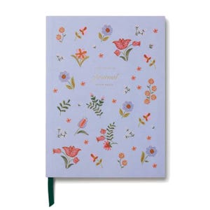 A lavender journal adorned with colorful floral patterns, featuring the word \“Journal\“ in gold lettering, and a dark green ribbon bookmark.