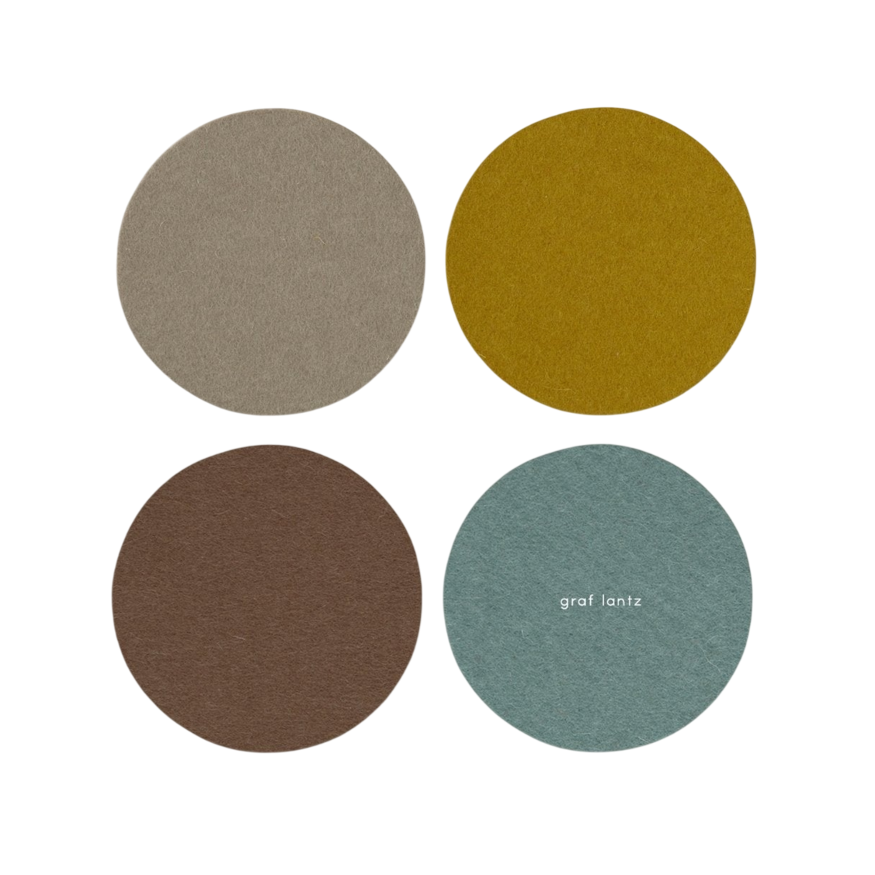 Set of four round felt coasters in neutral colors; one coaster has \“graf lantz\“ printed on it.