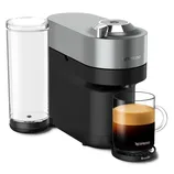 A Nespresso coffee machine by Breville with a sleek design, featuring a cylindrical water tank and a glass cup filled with coffee placed on its tray.