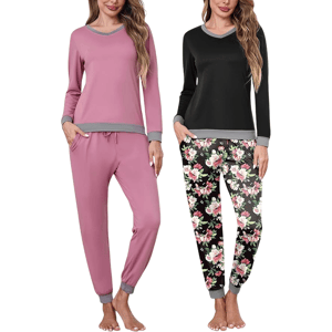 Two women are wearing comfortable pajama sets; one is pink with grey accents, and the other is a black top with floral-print pants, both featuring long sleeves and cuffed hems.