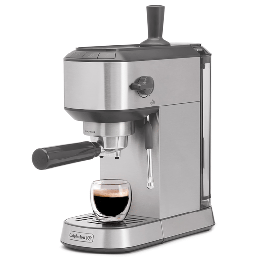 Espresso machine by Calphalon, featuring a portafilter handle, steam wand, and a removable water tank. A glass cup with espresso is placed on the drip tray.