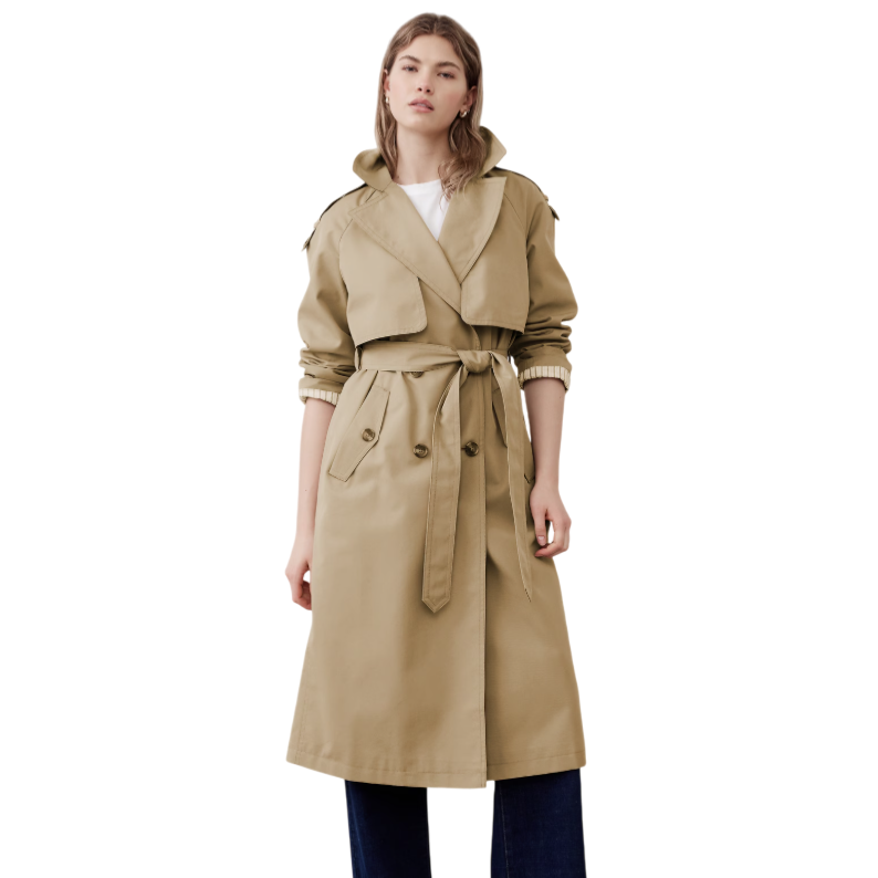 A person is wearing a beige trench coat with a tie belt, over rolled-up dark blue pants and black shoes, complemented by a white shirt.