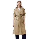 A person is wearing a beige trench coat with a tie belt, over rolled-up dark blue pants and black shoes, complemented by a white shirt.