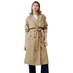 A person is wearing a beige trench coat with a tie belt, over rolled-up dark blue pants and black shoes, complemented by a white shirt.