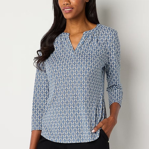 A woman is wearing a blue and white geometric print V-neck blouse with three-quarter sleeves.