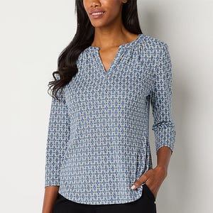 A woman is wearing a blue and white geometric print V-neck blouse with three-quarter sleeves.