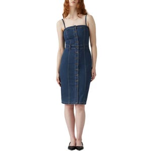 A knee-length denim dress with spaghetti straps, button-down front, and a matching belt, worn by a person, paired with black flat shoes.