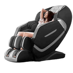 A person is reclined in a high-tech massage chair, designed with black and silver cushioning, featuring leg and foot rest components.