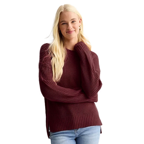 A woman is wearing a maroon knit sweater with long sleeves and light blue jeans.