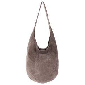 The Sak Suede Hobo bag features a soft, taupe-colored suede material with a relaxed, rounded shape and a single shoulder strap.