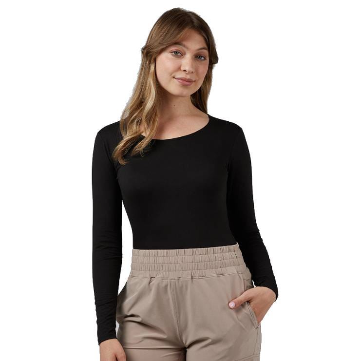 A person is wearing a black long-sleeve top and beige pants with an elastic waistband, posing with one hand in a pocket.