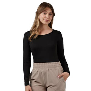 A person is wearing a black long-sleeve top and beige pants with an elastic waistband, posing with one hand in a pocket.